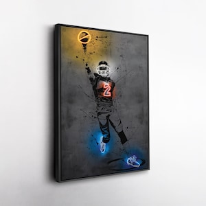 May include: Framed artwork featuring a football player in action, rendered in a neon-style illustration. The player is wearing a helmet and jersey with the number 2. The artwork uses a dark gray background with splashes of color, including yellow, orange, and blue.