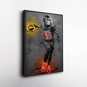 May include: A framed artwork featuring a football player in a dynamic pose. The player is depicted in a neon-style illustration with the number 10 on the jersey. The artwork uses a gray and black color scheme with neon yellow and red accents.