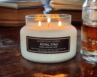 May include: A three-wick candle in a clear glass jar with a white wax fill. The black label reads Glowstone Candle, Royal Stag, Whiskey | White Oak | Vanilla, Hand-poured in TX, All-natural coconut/soy wax, 30+ hr burn time, 11oz, 312g.
