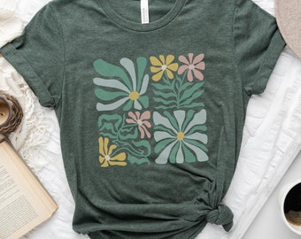 May include: A dark green t-shirt with a colorful abstract floral design printed on the front. The design features a variety of flowers in shades of pink, yellow, blue, and green.