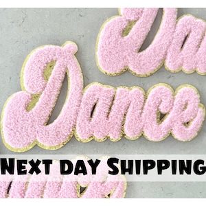 Pode incluir: Patches de ferro de veludo rosa que soletram "Dance" com acabamento dourado de glitter. Envio no dia seguinte.