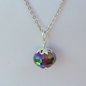 May include: A silver chain necklace with a purple iridescent glass bead pendant. The bead is faceted and has a silver filigree design around it.