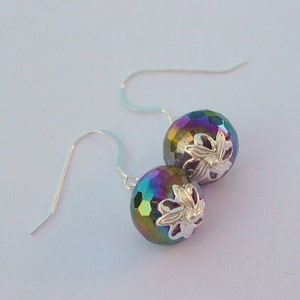 May include: A pair of iridescent silver earrings with a floral design. The earrings are made of faceted glass beads and silver wire.