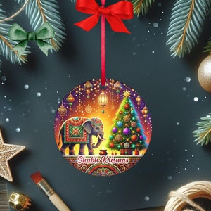 May include: A round Christmas ornament with a festive design. It features an elephant with ornate patterns, a decorated Christmas tree, and the text "Shubh Krismas". The ornament hangs from a red ribbon.