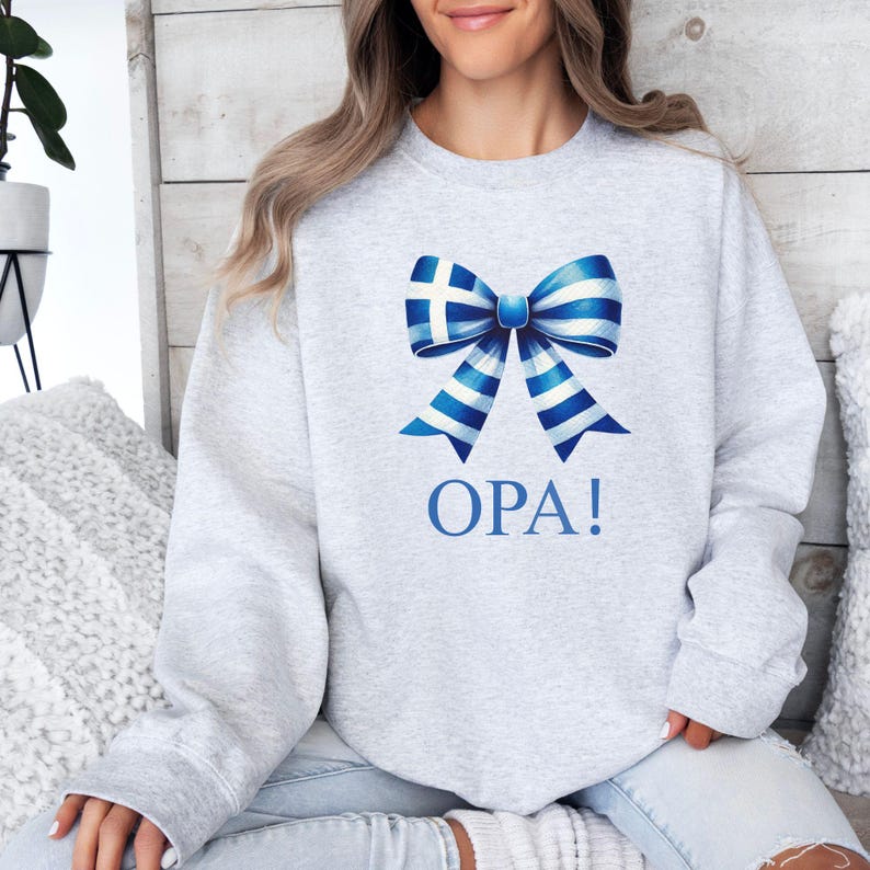 May include: A gray sweatshirt with a blue and white bow featuring the Greek flag and the word "OPA!" printed on the front.