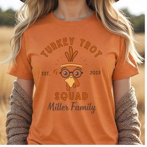 May include: Orange t-shirt with a turkey-themed graphic. The design includes the words "TURKEY TROT" above a cartoon turkey wearing glasses and the words "SQUAD Miller Family" below. The year "2025" is also included.