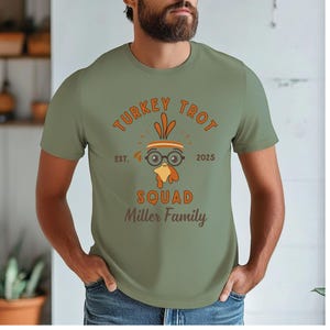 May include: Olive green t-shirt with the text "TURKEY TROT SQUAD" and a cartoon turkey wearing glasses. The text "EST. 2025 Miller Family" is also printed on the shirt. The shirt is short-sleeved.