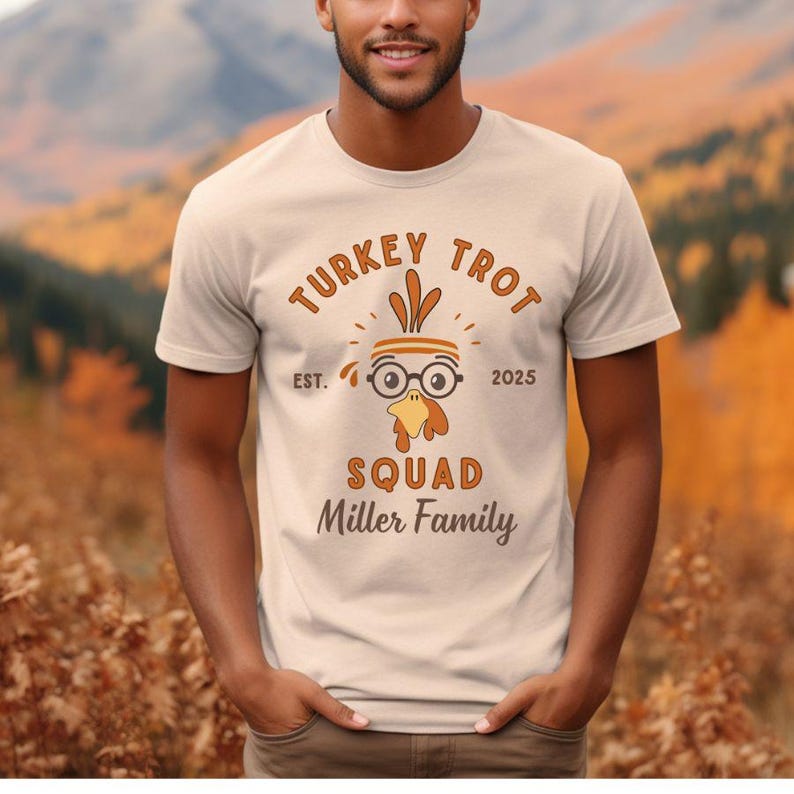 May include: Beige t-shirt with the text "TURKEY TROT SQUAD Miller Family" in brown. The design includes a cartoon turkey head wearing glasses and a headband. The shirt also has "EST. 2025" printed on it.