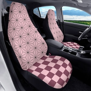May include: Car seat covers featuring a pink and black geometric design on the seat backs and a pink and burgundy checkerboard pattern on the seat bases. The car interior is visible, with a steering wheel and a view of the sky.