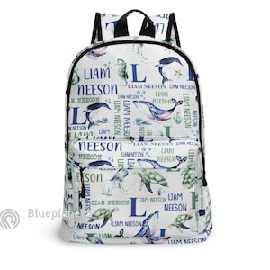 Könnte beinhalten: Weißer Rucksack mit einem blauen und grünen Meereslebewesen-Muster. Der Rucksack zeigt einen Wal, ein Seepferdchen und eine Schildkröte. Der Name "Liam Neeson" wird im gesamten Muster wiederholt.