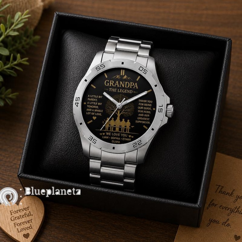 May include: A silver-tone stainless steel wristwatch with a black dial featuring gold-colored text that reads GRANDPA THE LEGEND, along with a tree graphic, a silhouette of people on a bench, and the names LIAM, SOPHIA, ETHAN, and OLIVIA.