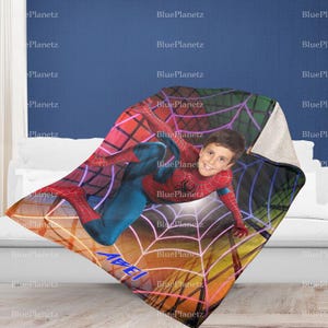 May include: A red and blue Spiderman blanket with a child's face superimposed on the character's face. The blanket has a web design with neon pink and purple accents. The child's name, "Abe", is written in white on the blanket.