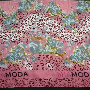 Könnte beinhalten: Rosa-weißer Schal mit Leopardenmuster und Blumendesign. Der Schal trägt den Schriftzug "Mia Moda".