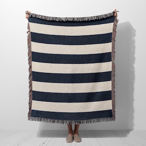 May include: A woven throw blanket with navy blue and white stripes and fringe on all sides.