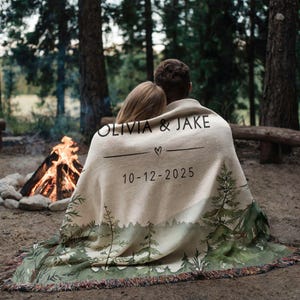 Personalized wedding blanket with names and date, forest design woven cotton throw displayed outdoors near lake