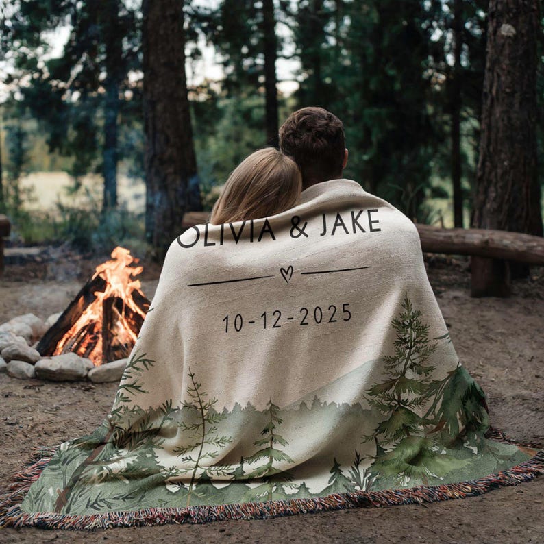 Personalized wedding blanket with names and date, forest design woven cotton throw displayed outdoors near lake