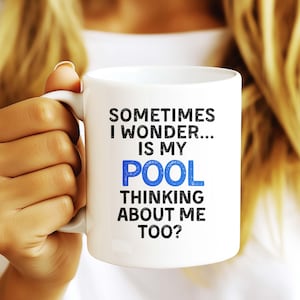 May include: A white ceramic mug with a black handle and the text "But First, Coffee" in a bold, black font. The mug is set against a blurred background, suggesting a cozy setting. The mug appears to be approximately 4 inches tall.
