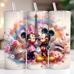 May include: Two stainless steel tumblers with a colorful design featuring Mickey and Minnie Mouse in front of the Eiffel Tower. The background is a watercolor-style design with pink, blue, and yellow colors. The tumblers have a straw and a lid.