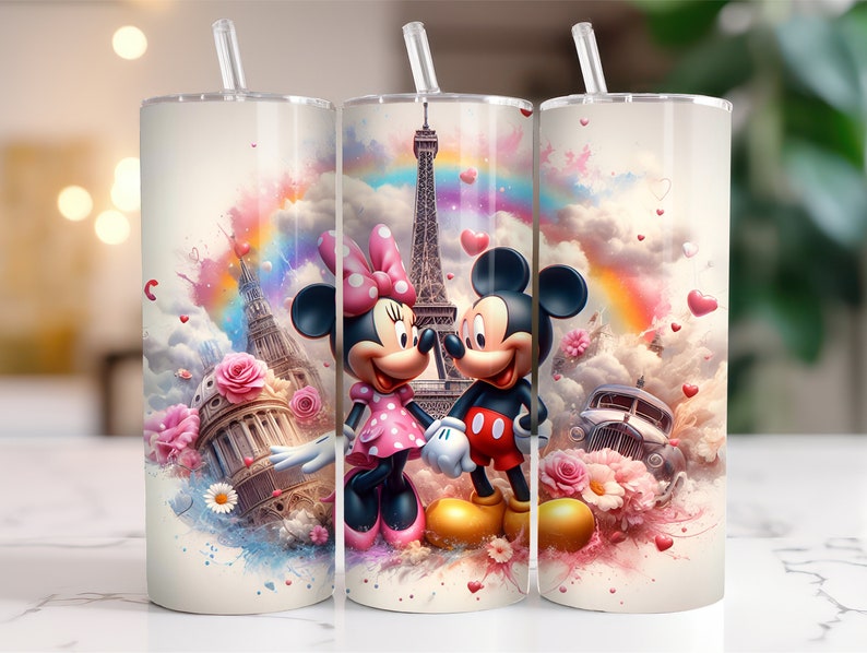 May include: Two stainless steel tumblers with a colorful design featuring Mickey and Minnie Mouse in front of the Eiffel Tower. The background is a watercolor-style design with pink, blue, and yellow colors. The tumblers have a straw and a lid.