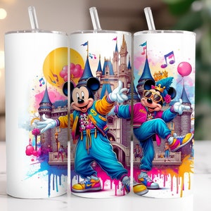 May include: White tumbler featuring a vibrant design of Mickey Mouse posing in front of a castle. Mickey is dressed in a blue tracksuit and yellow jacket. The design includes musical notes and paint splatters.