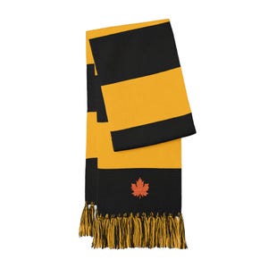 May include: A knitted scarf featuring wide horizontal stripes in black and golden yellow. The scarf is finished with a fringe of alternating black and yellow tassels at the ends and displays a small, embroidered orange maple leaf emblem.