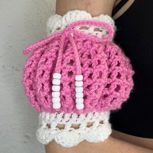 May include: Pink crocheted arm warmer with white crocheted trim and white beads.