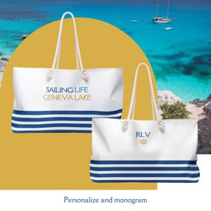 May include: Two white canvas tote bags with blue stripes. One bag says "Sailing Life Geneva Lake" and the other has the initials "RLV" with a nautical wheel design.