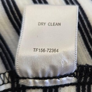 May include: A close-up of a white fabric label with the words "DRY CLEAN" printed in black. Below the text is the number "TF156-72364". The label is attached to a black and white striped fabric.