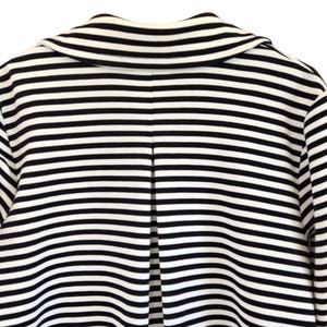 May include: A close-up shot of a black and white striped jacket. The jacket has horizontal stripes and a notched collar. The back of the jacket is visible, showing a split seam detail. The fabric appears to be a medium weight material.