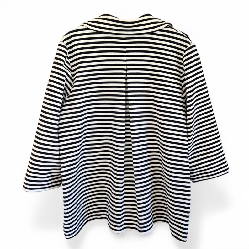 May include: A black and white striped jacket with a wide collar and three-quarter sleeves. The jacket has a vertical pleat in the back, and the stripes are horizontal across the body and sleeves. The jacket is displayed against a white background.