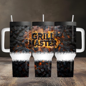 May include: A stainless steel tumbler with a handle and straw, featuring a graphic print of glowing charcoal briquettes and flames. The text "GRILL MASTER" is prominently displayed in bold, dark letters across the center of the fiery design.