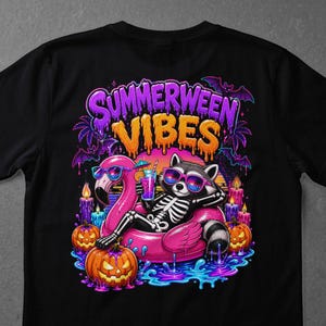May include: Black t-shirt featuring a raccoon skeleton wearing sunglasses, relaxing on a pink flamingo float with a cocktail. The shirt has the text "Summerween Vibes" with bats, candles, and jack-o'-lanterns.