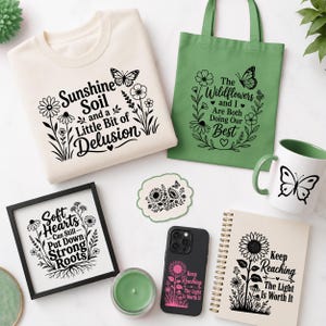 Pode incluir: Uma coleção de itens incluindo uma sweatshirt creme, um saco de pano verde, uma caneca branca com interior verde, uma impressão emoldurada, um autocolante, uma capa de telemóvel preta e um caderno de espiral, com desenhos florais pretos.