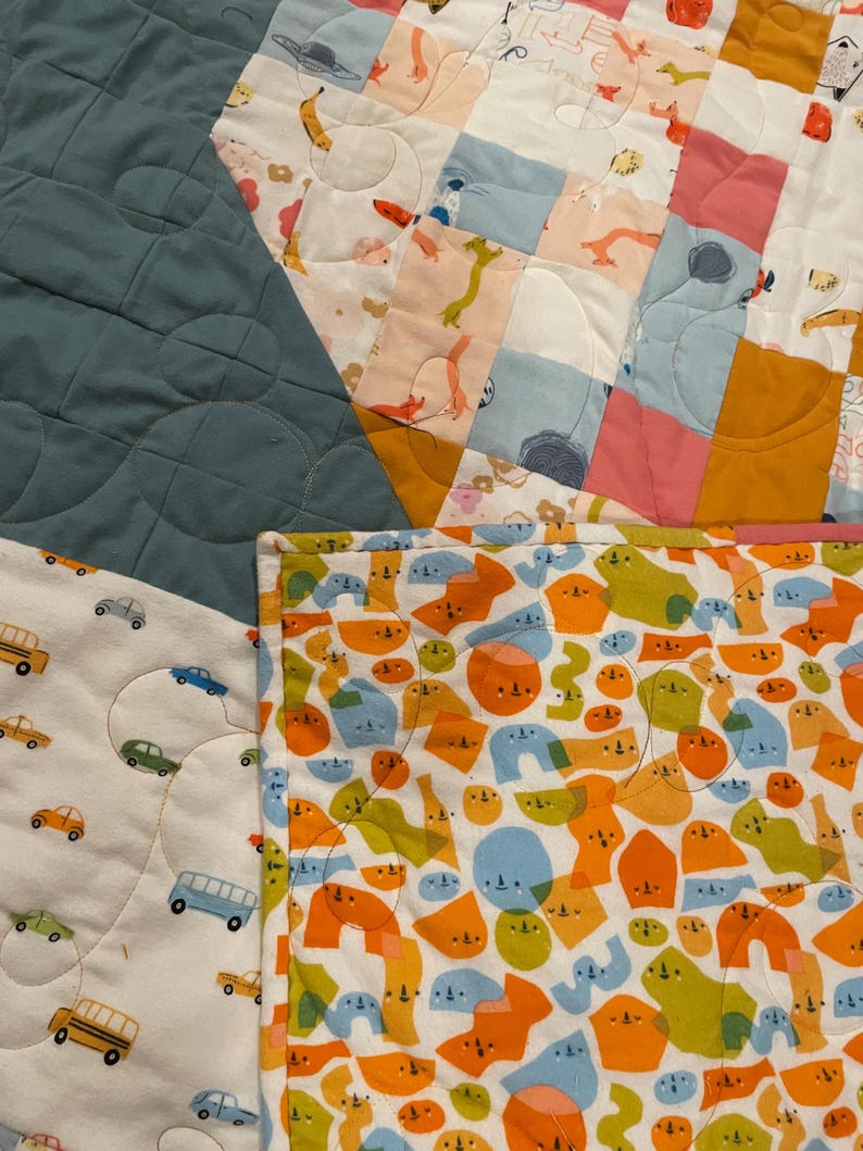 May include: A patchwork quilt with a variety of colorful fabrics. The quilt is made up of squares and rectangles, and features a variety of patterns, including animals, geometric shapes, and abstract designs. The quilt is a great way to add a touch of color and personality to any room.