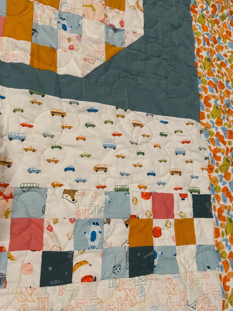 May include: A patchwork quilt with a variety of colorful fabrics and patterns. The quilt features a blue, yellow, and pink color scheme. The quilt is made up of squares and rectangles, and the fabric is quilted with a variety of designs. The quilt is a great way to add a touch of color and personality to any room.