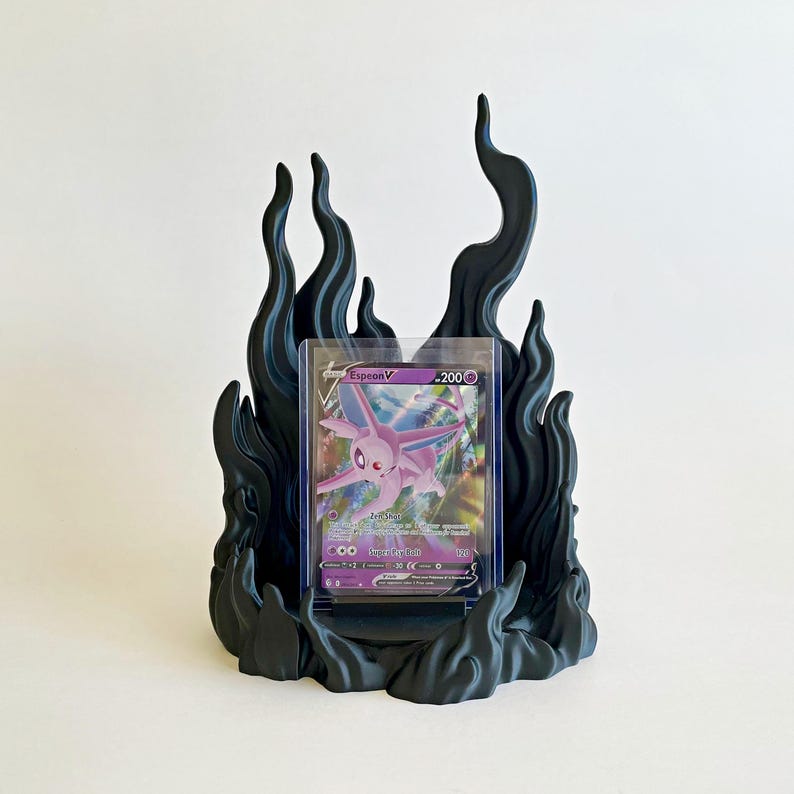 May include: A matte black display stand shaped like stylized flames, holding a clear plastic protective case containing a purple Espeon V trading card. The card features the character Espeon, the text Espeon V, and a health value of 200.