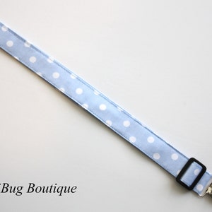 May include: A light blue and white polka dot fabric baby pacifier clip with silver clips.