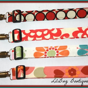 May include: Four fabric straps with metal clips and black buckles. The straps feature different colorful patterns, including red, white, orange, green, blue, and pink.