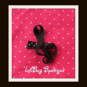 May include: Black and white polka dot ribbon shaped into a treble clef on a pink background with white polka dots. The text "Lil Bug Boutique" is written in white on the pink background.