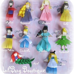 Könnte beinhalten: Ein Set aus zehn bunten Haarbändern mit Disney-Prinzessinnen. Die Schleifen sind aus Band gefertigt und in Form der Prinzessinnenkleider gestaltet. Die abgebildeten Prinzessinnen sind Mulan, Rapunzel, Aurora, Belle, Schneewittchen, Aschenputtel, Jasmin, Tinkerbell, Arielle und Alice.