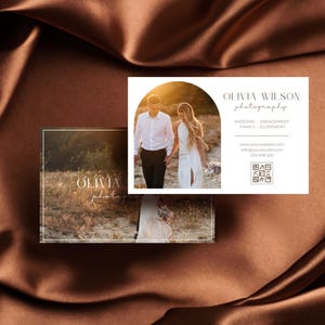 May include: A white business card with a photo of a couple walking on a beach at sunset. The text on the card reads "Olivia Wilson Photography" and includes contact information and a QR code.