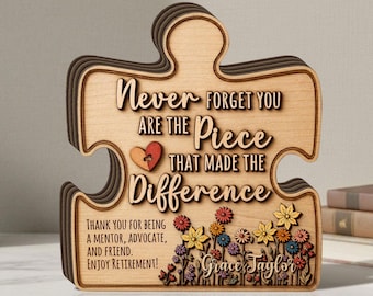 Puede incluir: Una placa de madera en forma de pieza de rompecabezas con el texto "Never forget you are the piece that made the difference", un pequeño icono de corazón, un diseño floral y el nombre personalizado "Grace Taylor" grabado en el frente.