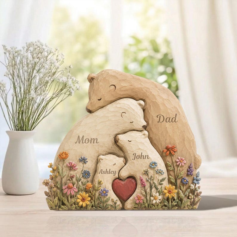 K&ouml;nnte beinhalten: Eine B&auml;renskulptur f&uuml;r die Familie mit den Worten "Mom", "Dad", "Ashley" und "John" in die B&auml;ren geschnitzt. Die Skulptur zeigt ein Herz und ist von bunten Blumen umgeben. Die B&auml;ren sind in Braun- und Cremet&ouml;nen gehalten.