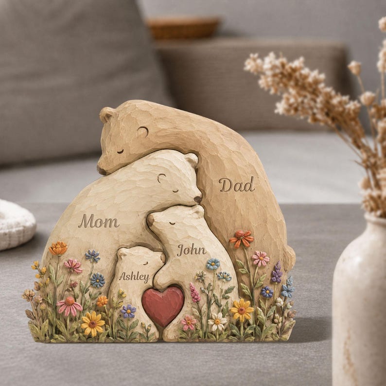 K&ouml;nnte beinhalten: Eine geschnitzte Holzskulptur einer B&auml;renfamilie mit den Worten "Mom", "Dad", "John" und "Ashley". Die B&auml;ren sind von bunten Blumen und einem roten Herzen umgeben.