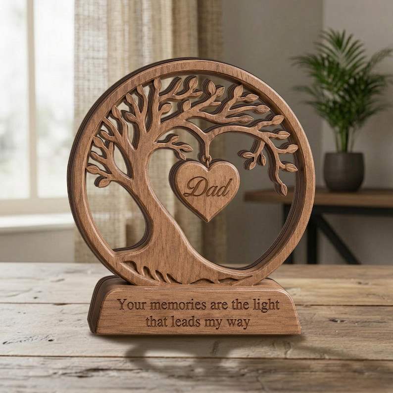 May include: A circular wooden ornament featuring a laser-cut tree design with a heart-shaped pendant hanging from the branches. The heart is engraved with the word Dad. The base is engraved with the text: Your memories are the light that leads my way.