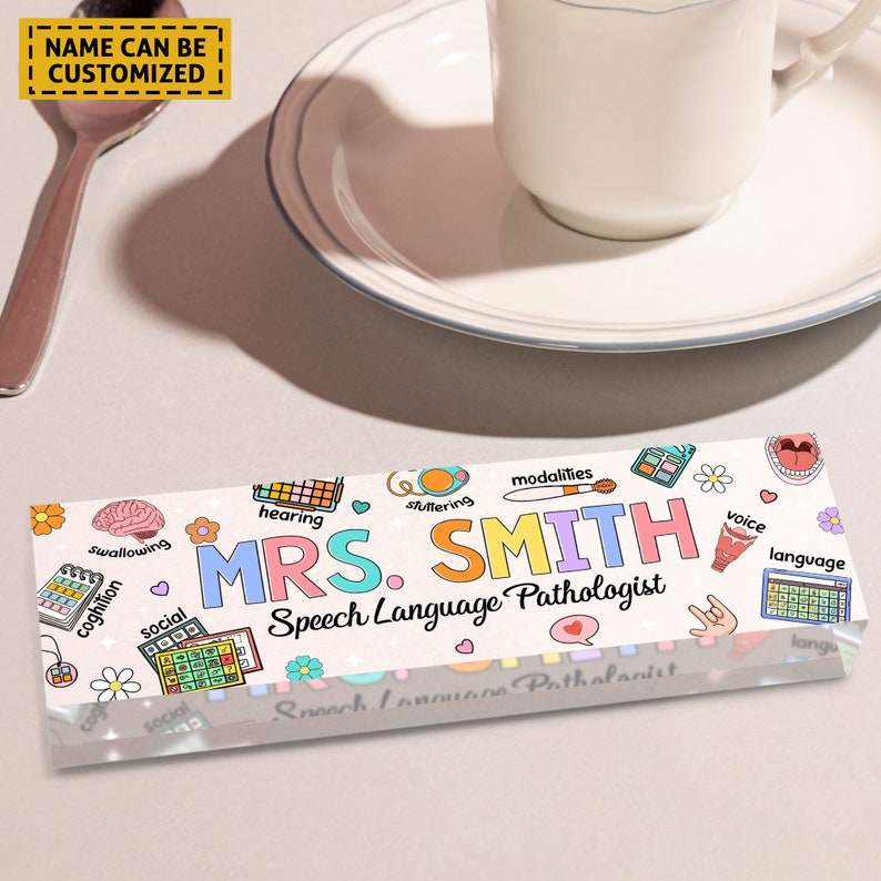 May include: A white acrylic desk plaque with colorful illustrations of speech therapy related icons and the text "MRS. SMITH Speech Language Pathologist".