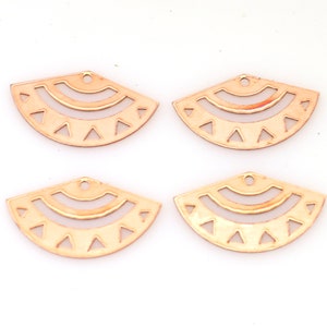 May include: Four gold-colored metal charms in the shape of a half-circle with a geometric design. Each charm has a hole at the top for attaching to jewelry.