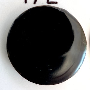 May include: A black round ceramic tile with the number 472 printed on a white background.