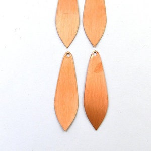 May include: Four copper-colored teardrop-shaped metal pendants with a hole at the top for hanging.