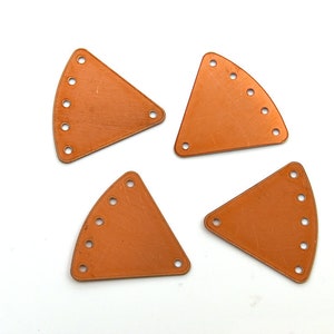 May include: Four copper-colored metal triangle shapes with rounded edges and multiple holes along the edges.